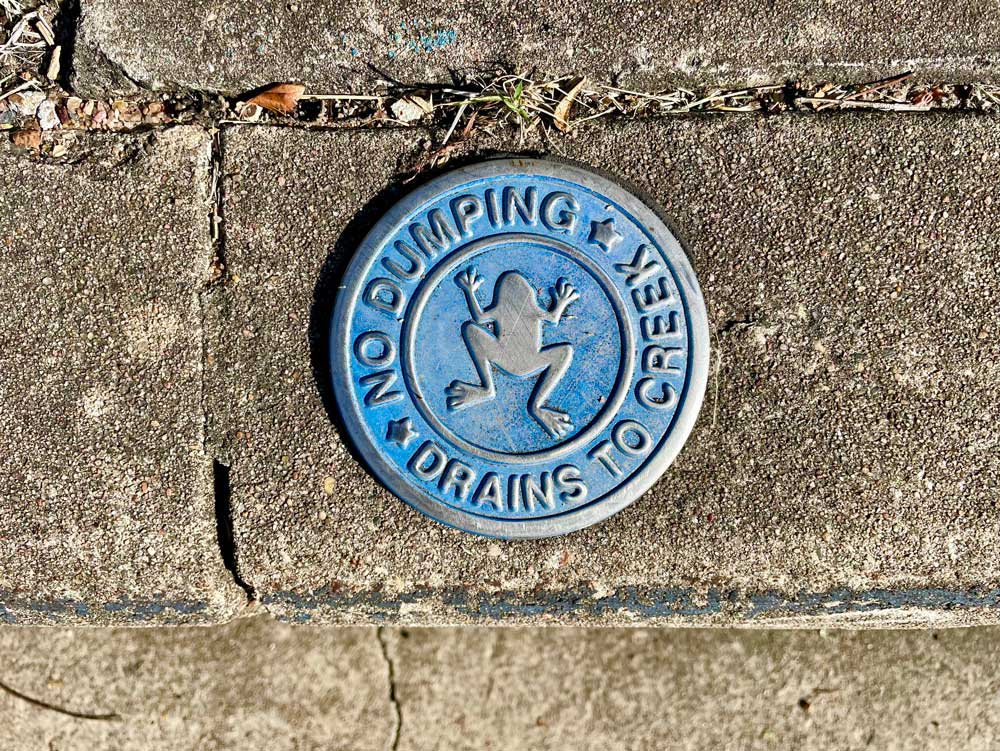 Photo of plaque that reads 'No Dumping - Drains to Creek'